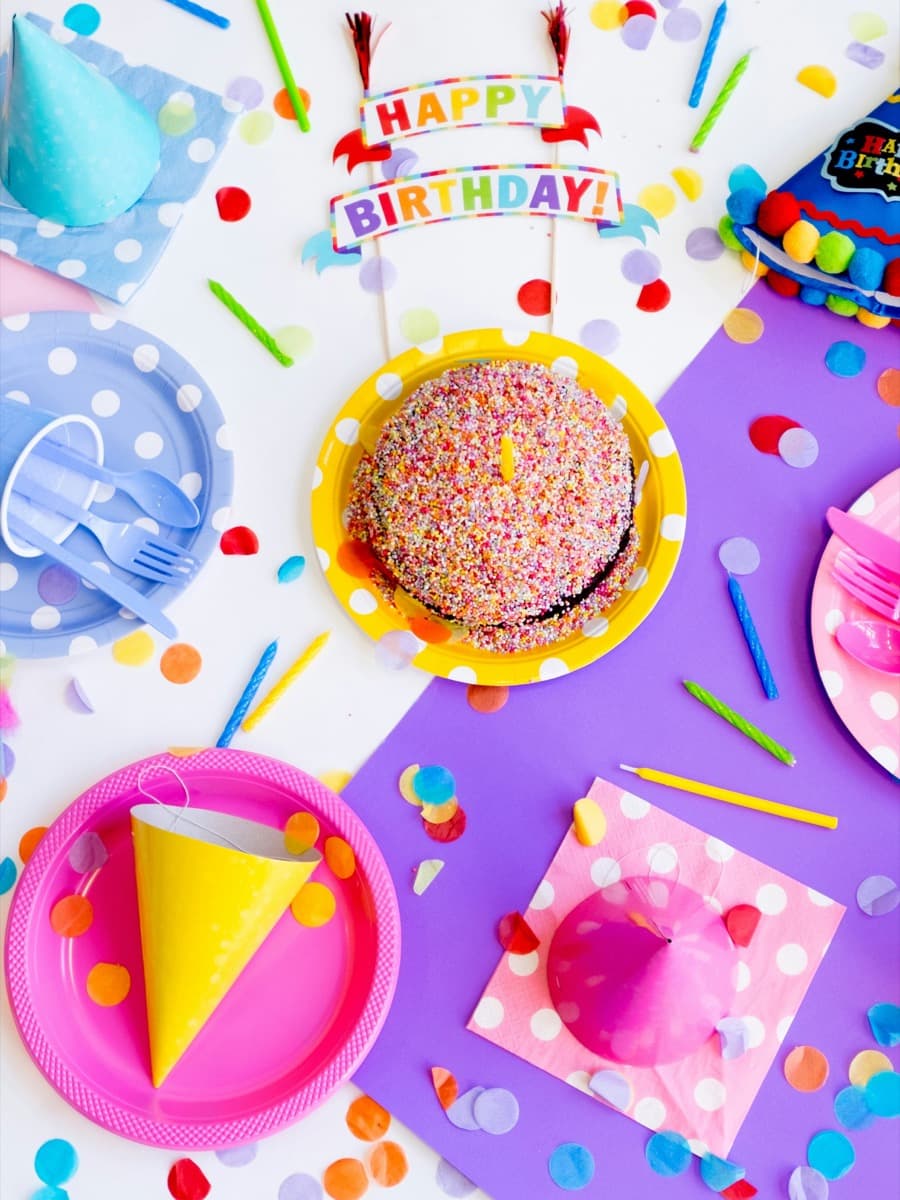 Mesa de fiesta con platos, gorritos y confeti